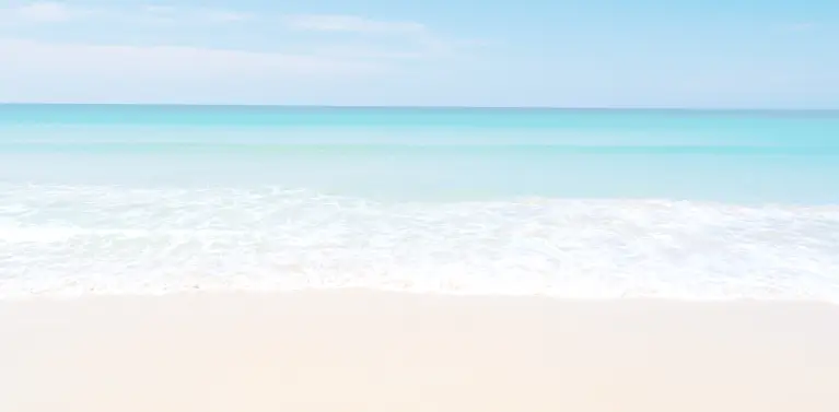 A beach with blue water and blue sky